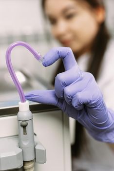 Hand in Blue latex glove and saliva ejector symbolize love in dentistry. Heart symbol. Dental treatment, healthcare and dentistry concept