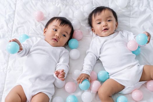 cheerful twin babies playing color ball on bed