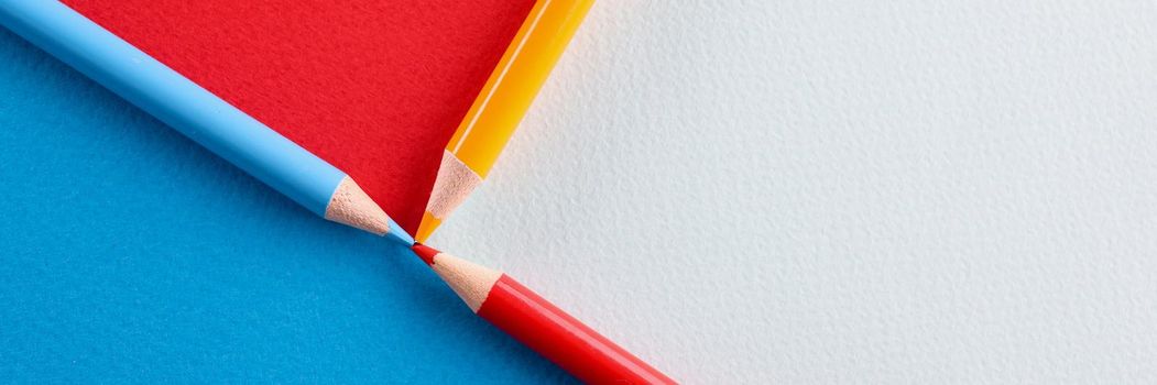 Multicolored pencils lying on paper background closeup