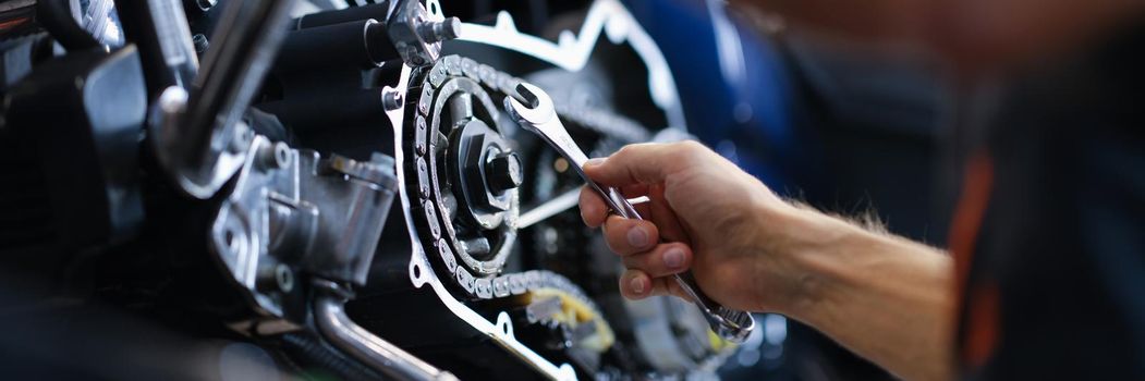 Master repairman repairing motorcycle with wrench closeup