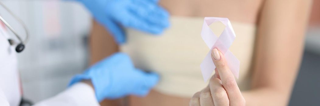 Doctor gynecologist examining patient breast with pink tape closeup