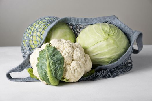 Heads of white cabbage and cauliflower in an eco-friendly mesh bag