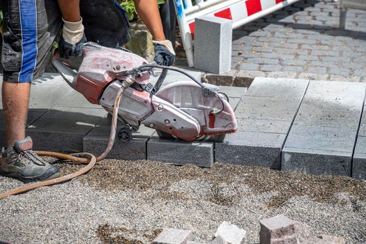 A worker cuts a tile to size with an electric grinder to complete the self-locking paving