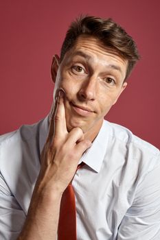Portrait of a young brunet man posing in a studio against a red background.