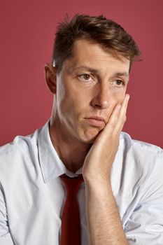 Portrait of a young brunet man posing in a studio against a red background.