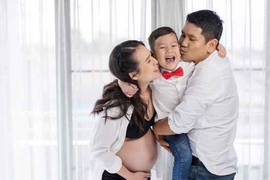 happy family concept, pregnant mother and father kissing boy