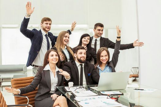 business team with their hands up and voting for decision-making near the desktop