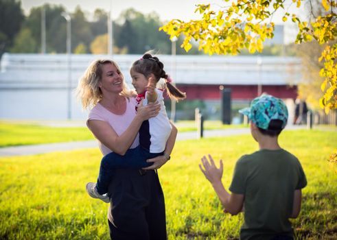 Mom plays and dances with children in the park, laughs and spins with happiness. Russia Moscow September 24, 2020