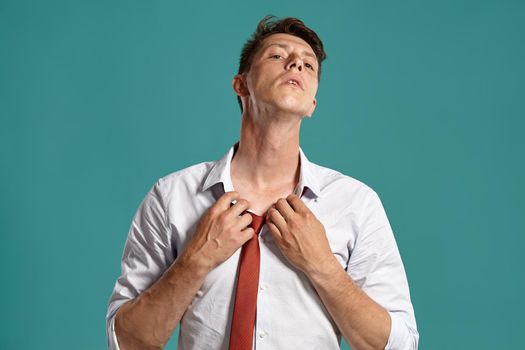 Portrait of a young brunet man posing in a studio against a blue background.