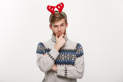 Holiday Concept - Young beard man in sweater with thoughtful gesture on white background.