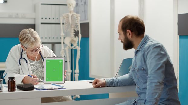Physician and patient analyzing digital tablet with greenscreen