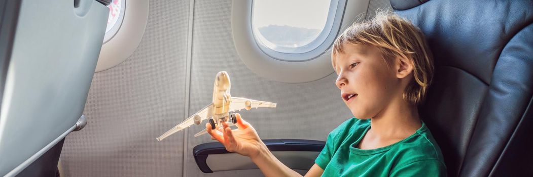 Little boy play with toy plane in the commercial jet airplane flying on vacation BANNER, LONG FORMAT