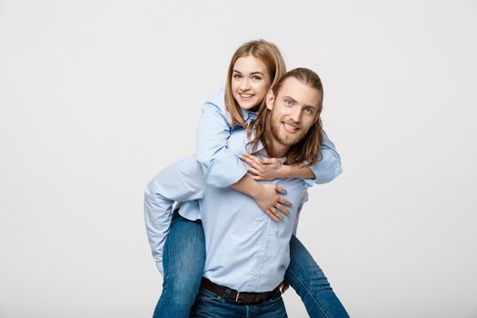 Portrait of smiling man giving happy woman a piggyback ride.