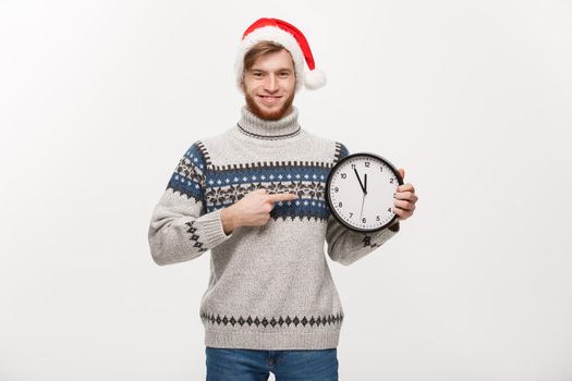 Holiday concept - Young handsome beard man pointing on white clock telling the time.