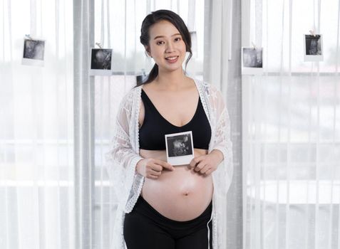 pregnant woman holding ultrasound scan photo