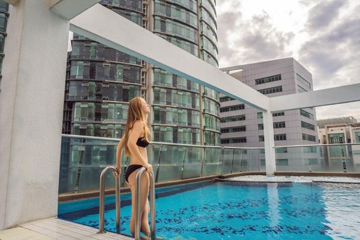 Malaysia, Kuala Lumpur November 21, 2018: Young woman in the pool among the skyscrapers and the big city. Relax in the big city. Rest from stress.