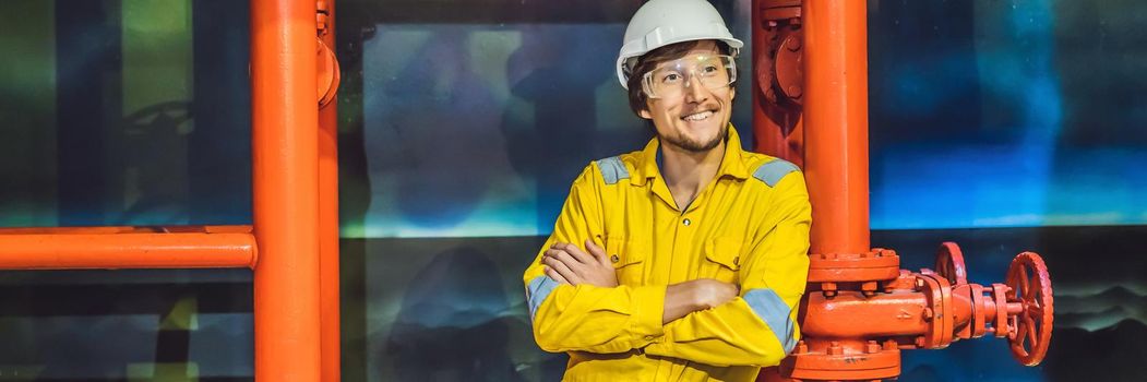 Young man in a yellow work uniform, glasses and helmet in industrial environment,oil Platform or liquefied gas plant BANNER, LONG FORMAT