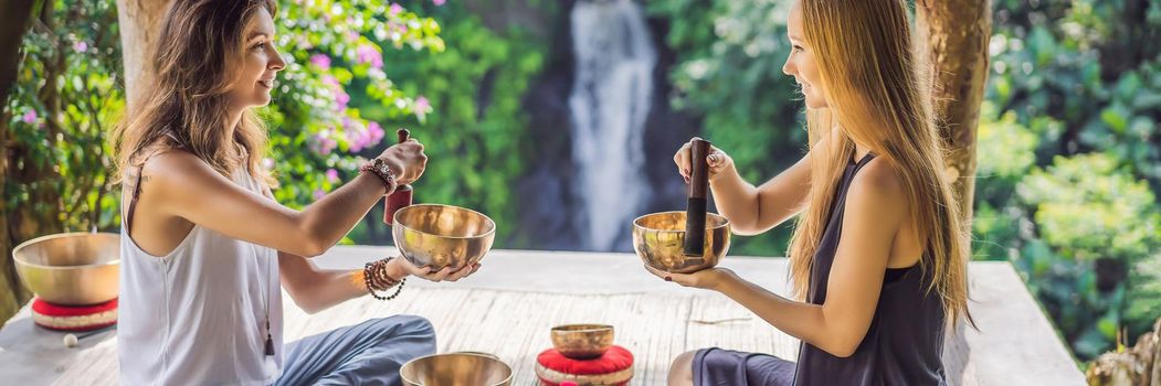 BANNER, LONG FORMAT Nepal Buddha copper singing bowl at spa salon. Young beautiful woman doing massage therapy singing bowls in the Spa against a waterfall. Sound therapy, recreation, meditation, healthy lifestyle and body care concept
