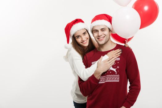 Christmas Concept - Young girlfriend holding balloon is hugging and playing with her boyfriend doing a surprise on Christmas