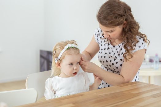Mother helps to put on cochlear implant for her deaf little daughter. Hearing aid and deafness concept