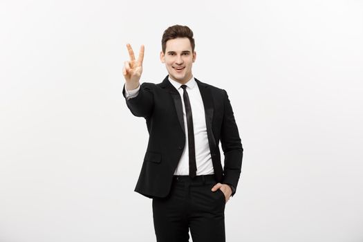Happy businessman showing two fingers or victory gesture, against grey background. Success in business, job and education concept. Blank copyspace area for advertisiment, slogan or text