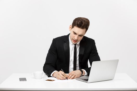 Business Concept: Portrait concentrated young successful businessman writing documents at bright office desk.