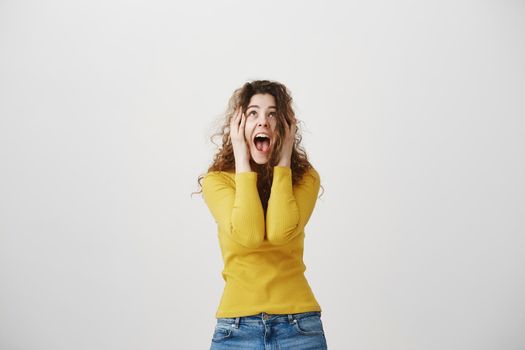 Portrait excited screaming young woman standing isolated over white background. Looking camera.