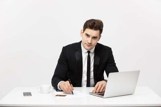 Business Concept: Portrait concentrated young successful businessman writing documents at bright office desk.