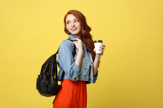 Happy young woman with a disposable coffee cup over isolated bright yellow background.