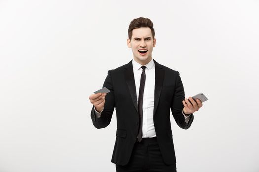 Angry businessman holding credit card and mobile phone. Get Mad while shopping online or business problem.