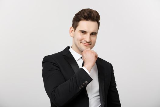 Business Concept: Smiling thoughtful handsome man standing on white isolated background and touching his chin with hand