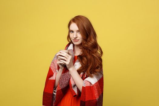 Lifestyle Concept: Portrait of woman basking with plaid and enjoy drinking chocolate Isolated over vivid yellow background