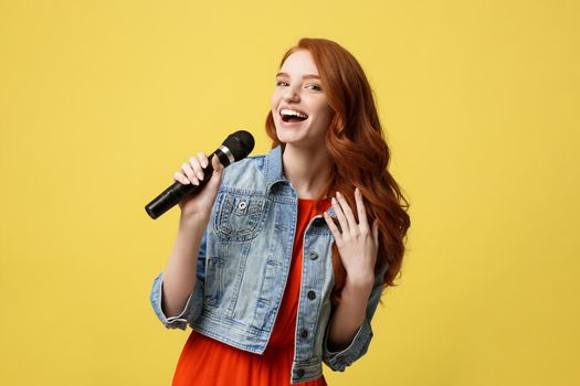 Lifestyle and People Concept: Expressive beauty ginger hair model girl in casual jean cloth singer with a microphone.