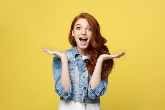 Lifestyle Concept: Smiling beautiful young woman in jean clothes posing with hands on chin. Isolated over yellow background.