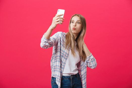 Charming young woman in white hat travel and take selfie on front camera smartphone posing isolated on shine pink background