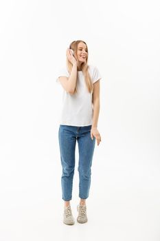 Lifestyle Concept: Portrait of a cheerful happy girl student listening to music with headphones while dancing isolated over white background