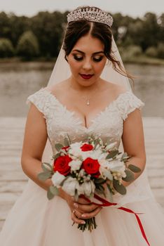 European Caucasian young black-haired woman bride girl holding her bouquet flowers in hands.