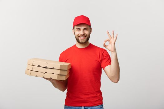 Delivery Concept: Handsome pizza delivery man making OK sign isolated over grey background.