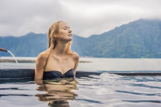Geothermal spa. Woman relaxing in hot spring pool against the lake. hot springs concept