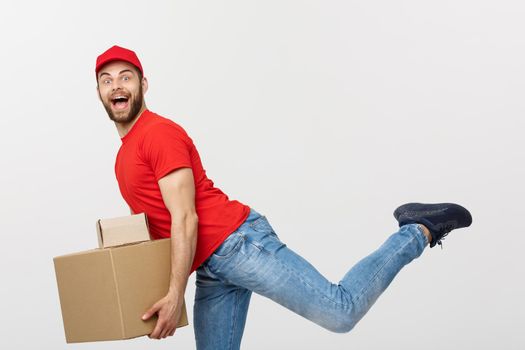 Delivery Concept - Handsome caucasian delivery man rush running for delivering a package for customer. Isolated on Grey studio Background. Copy Space.