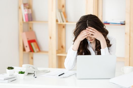 Tired young businesswoman suffering from long time sitting at computer desk in office
