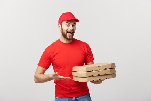 Delivery Concept: Young caucasian Handsome Pizza delivery man holding pizza boxes isolated over grey background