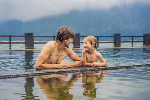 Dad and son travelers in Hot Springs in Bali on the background of lake. Traveling with children concept