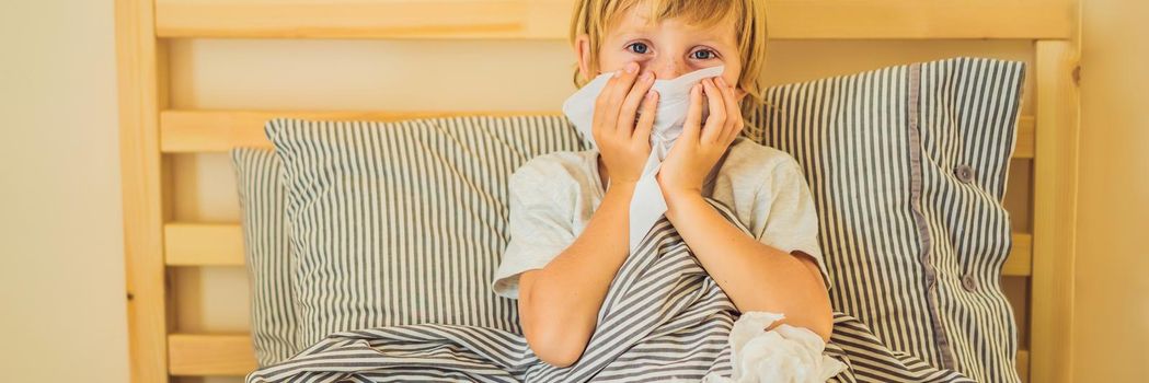 Sick boy coughs and wipes his nose with wipes. Sick child with fever and illness in bed BANNER, LONG FORMAT