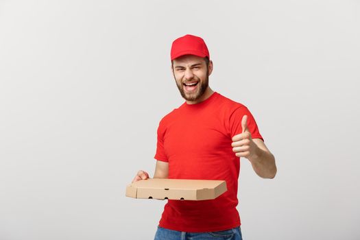 Pizza delivery concept. Young handsome delivery man showing pizza box and holding thumb up sign. Isolated on white background
