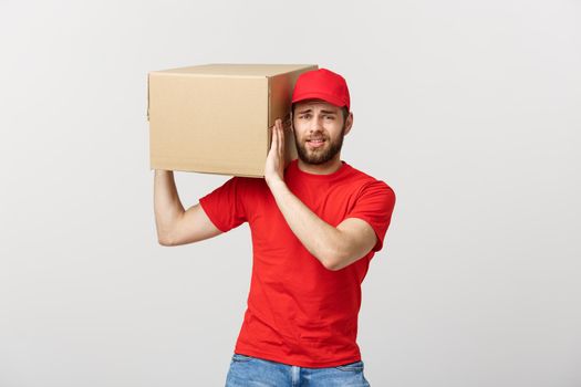 Delivery Concept: handsome Delivery man with boxes, delivery, courier with worry facial expression. Isolated grey background.