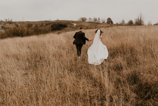 couple wedding newlyweds walk run on tall grass on mountain above the river
