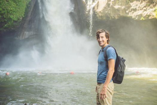 Man traveler on a waterfall background. Ecotourism concept