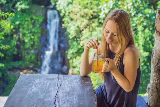 Closeup portrait image of a beautiful woman drinking ice tea with feeling happy in green nature and waterfall garden background