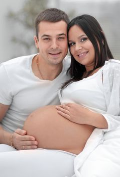 portrait of pregnant woman with husband sitting on the couch